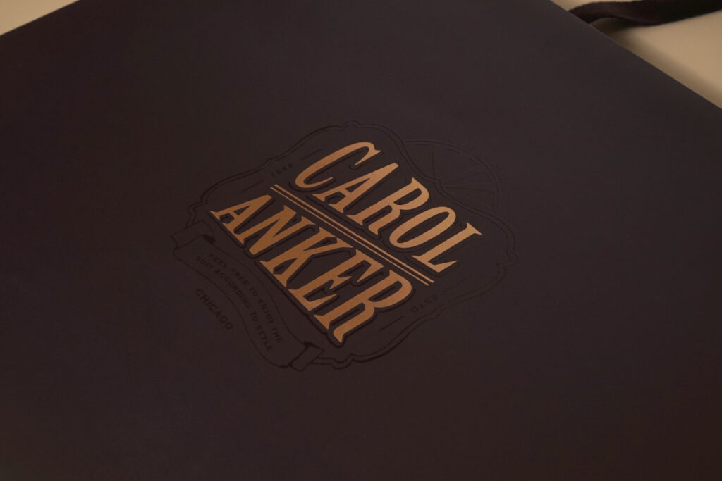 新作のサンプル紙袋が登場！スーツブランド「CAROL ANKER」のロゴに施されたUV加工と箔押し加工が高級感を生む魅力的なオリジナル紙袋